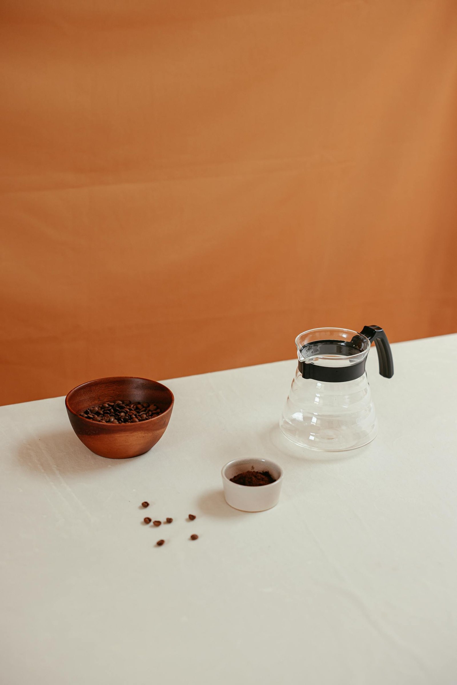 Clear Glass Pitcher Beside Brown Ceramic Bowl on White Table