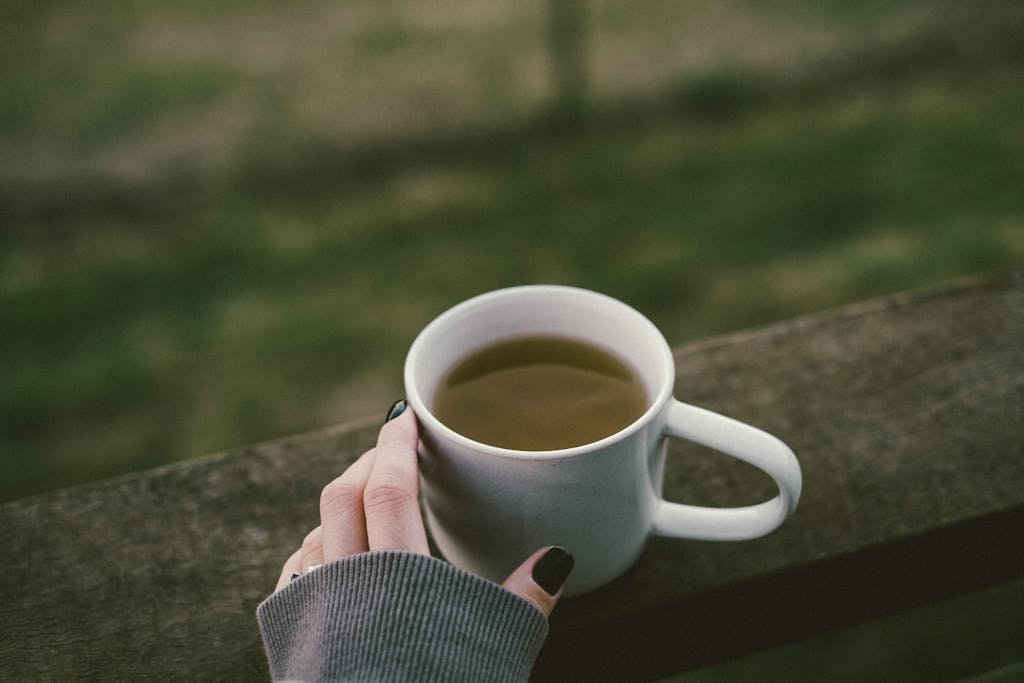 Closeup of a Female Hand with Morning Coffee on a Balustrade